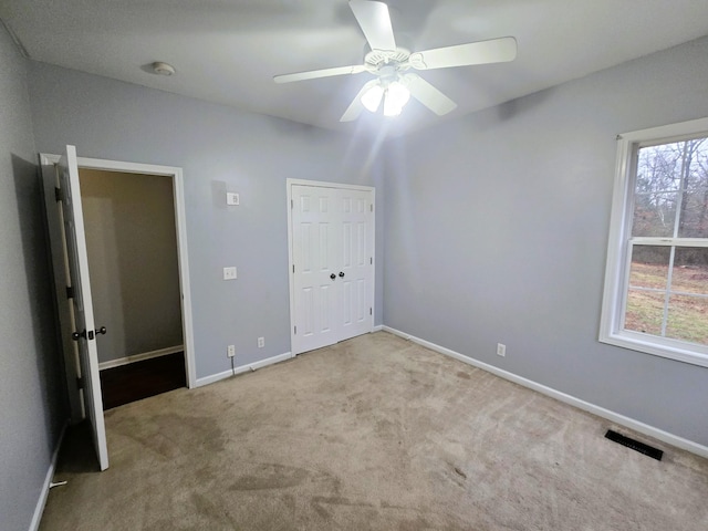 unfurnished bedroom featuring visible vents, a closet, baseboards, a ceiling fan, and carpet