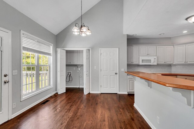 1031 Laurel Hill Dr, Dickson, TN 37055 - kitchen with white microwave, a chandelier, high vaulted ceiling, baseboards, and dark wood-style flooring