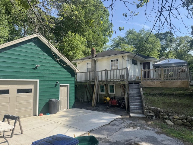rear view of property featuring a wooden deck, stairs, a chimney, and driveway