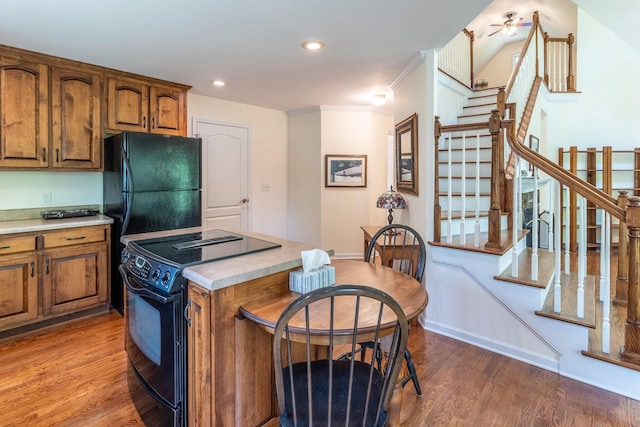 kitchen featuring light wood-style floors, light countertops, black appliances, and brown cabinets