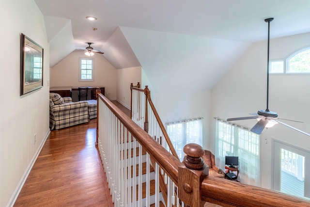 corridor with vaulted ceiling, wood finished floors, baseboards, an upstairs landing, and recessed lighting