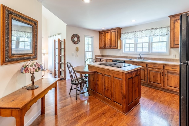 kitchen featuring brown cabinetry, a wealth of natural light, a sink, and a center island
