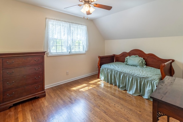 bedroom with baseboards, ceiling fan, wood finished floors, and vaulted ceiling