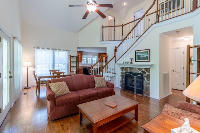 living area featuring stairs, ceiling fan, wood finished floors, and high vaulted ceiling