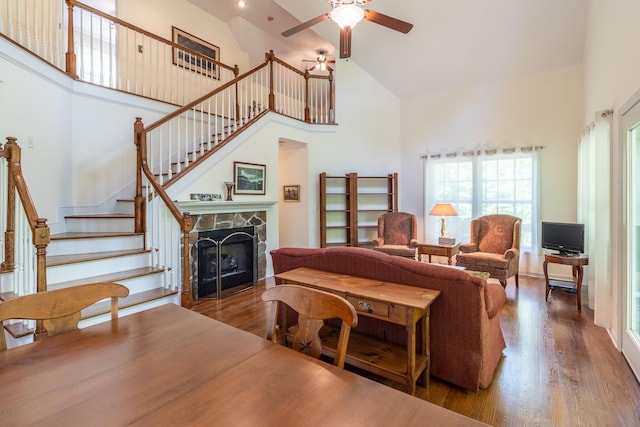 living room with stairs, wood finished floors, a healthy amount of sunlight, and high vaulted ceiling