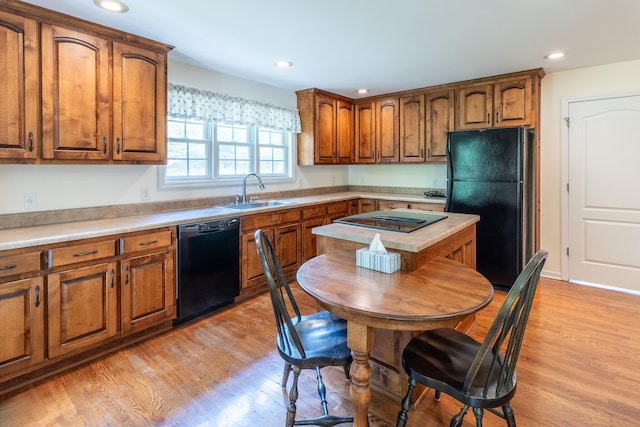 kitchen featuring a sink, brown cabinetry, black appliances, and light wood finished floors