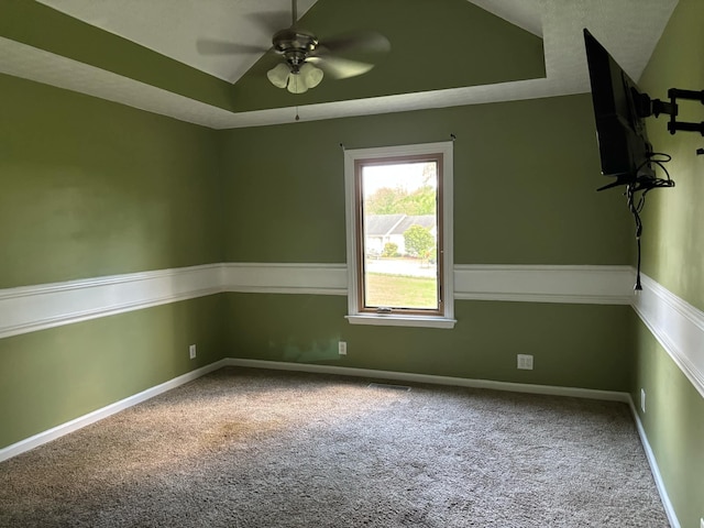 spare room featuring a raised ceiling, ceiling fan, and carpet flooring