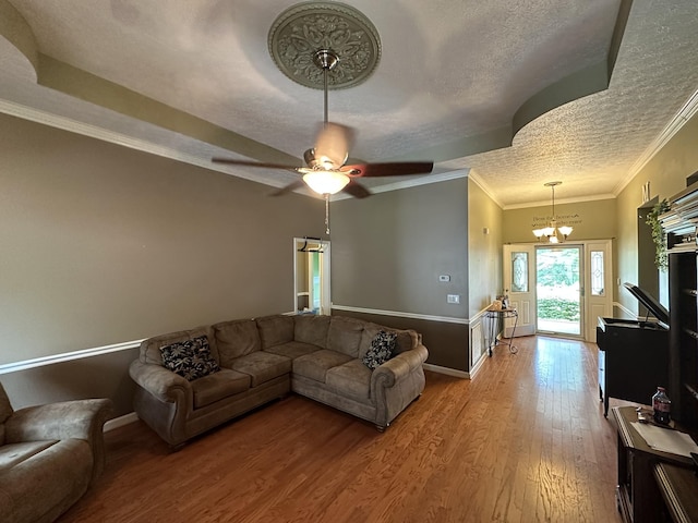 living room with a textured ceiling, ceiling fan with notable chandelier, baseboards, wood finished floors, and ornamental molding