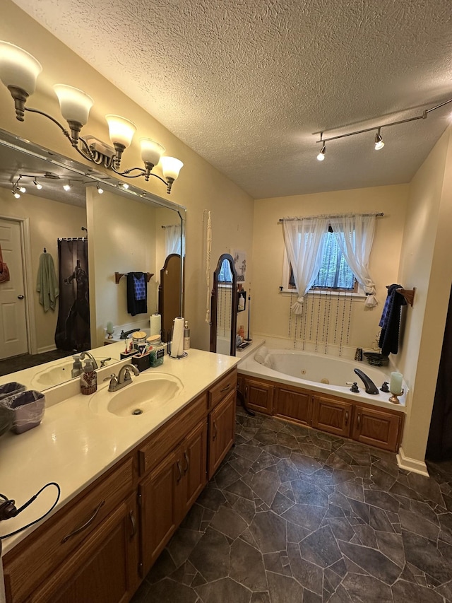 full bath featuring track lighting, a whirlpool tub, vanity, and a textured ceiling
