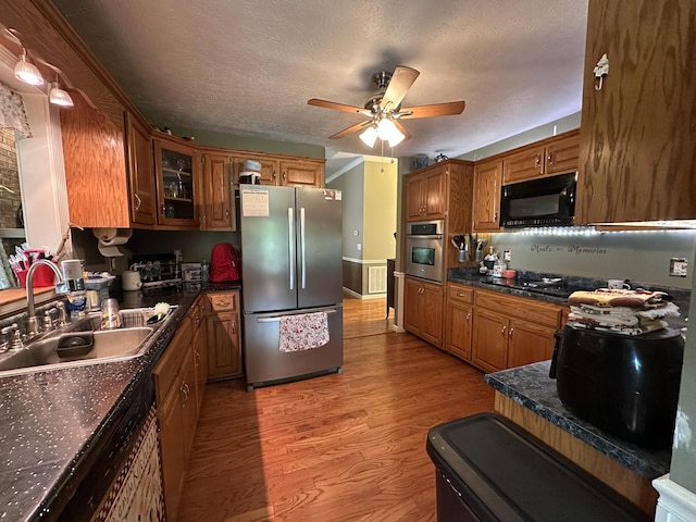 kitchen featuring ceiling fan, brown cabinetry, a sink, and black appliances