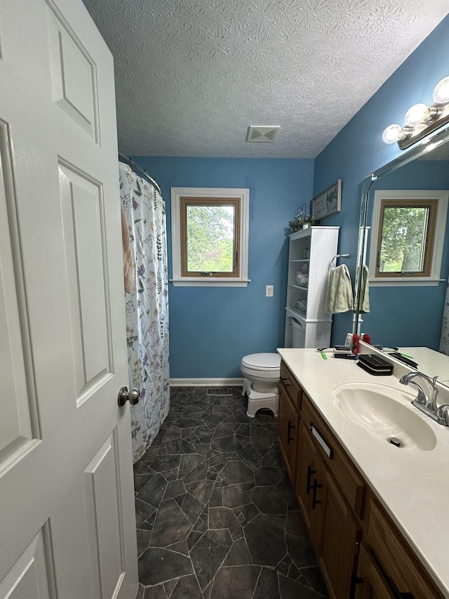 bathroom featuring visible vents, plenty of natural light, toilet, and vanity