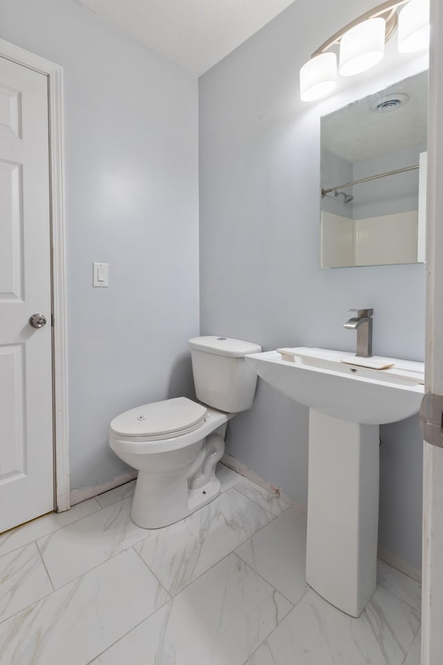 bathroom with baseboards, toilet, and marble finish floor