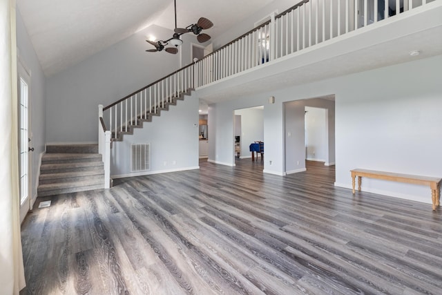 unfurnished living room featuring visible vents, wood finished floors, high vaulted ceiling, and stairway