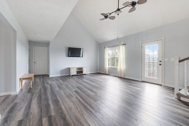 unfurnished living room with dark wood-type flooring, a ceiling fan, high vaulted ceiling, and stairway