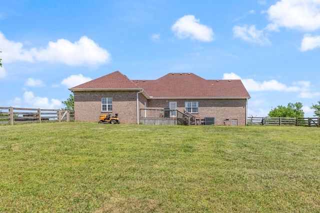 back of property with a lawn, brick siding, a fenced backyard, and central air condition unit
