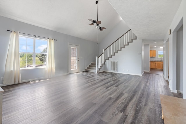 unfurnished living room with a ceiling fan, baseboards, wood finished floors, visible vents, and stairway