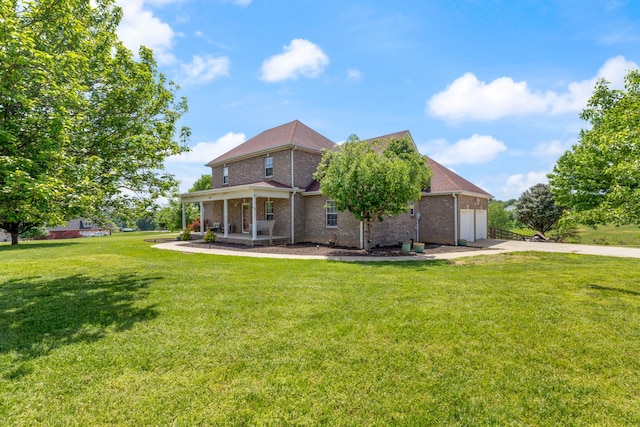 back of property with a porch, a yard, a garage, brick siding, and concrete driveway