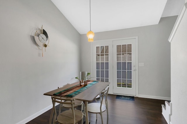dining room featuring dark wood-type flooring, baseboards, and vaulted ceiling