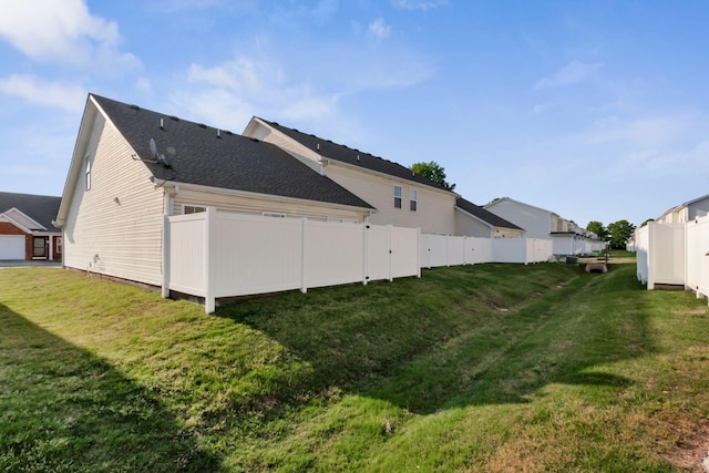 rear view of house with fence, a shingled roof, and a yard