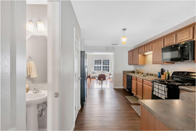 kitchen featuring a sink, dark wood finished floors, baseboards, visible vents, and black appliances