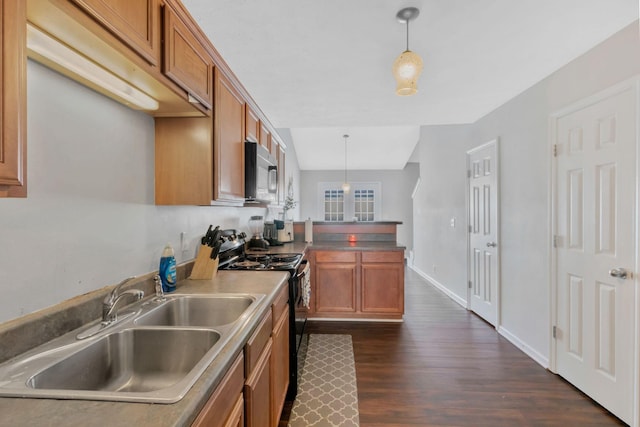 kitchen with hanging light fixtures, brown cabinetry, a sink, and black appliances