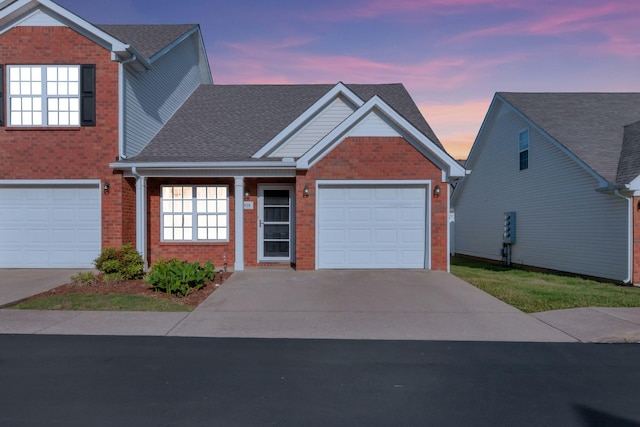 traditional home featuring brick siding, a shingled roof, an attached garage, and concrete driveway