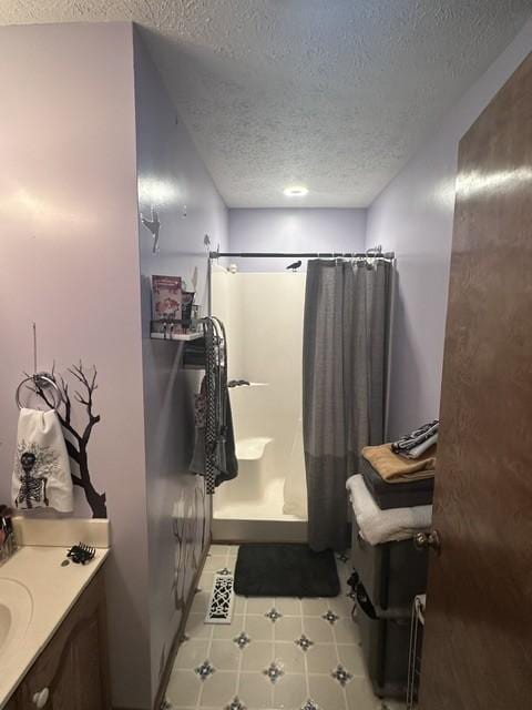 full bathroom with a textured ceiling, a shower with shower curtain, tile patterned flooring, and vanity