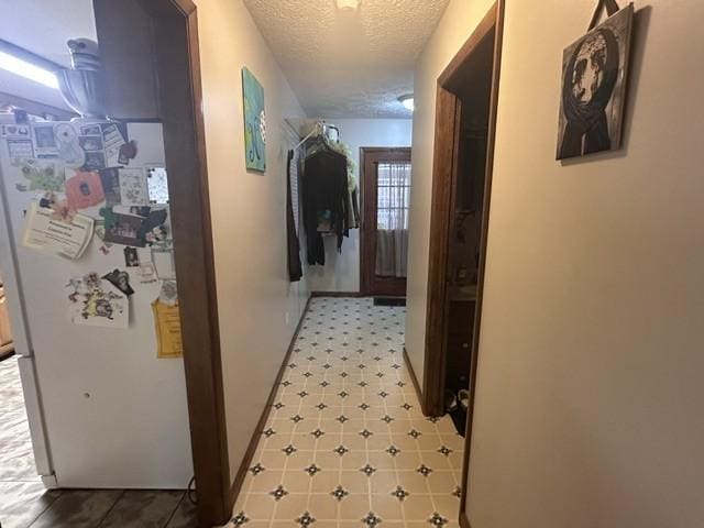 hallway with a textured ceiling and light floors