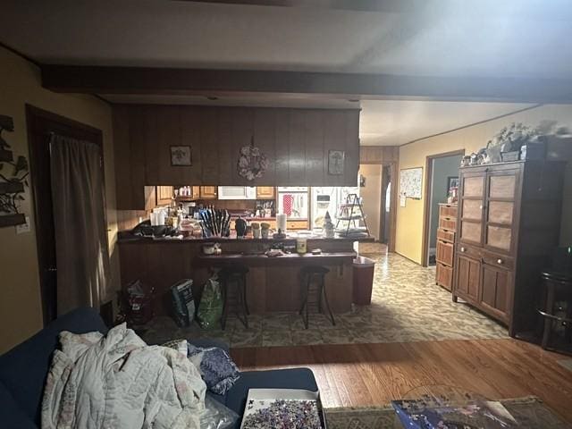 living room with beam ceiling, wood walls, and wood finished floors
