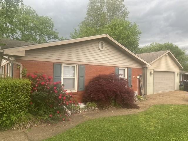 view of front of property with an attached garage, concrete driveway, and brick siding