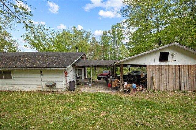rear view of house with a lawn and roof with shingles
