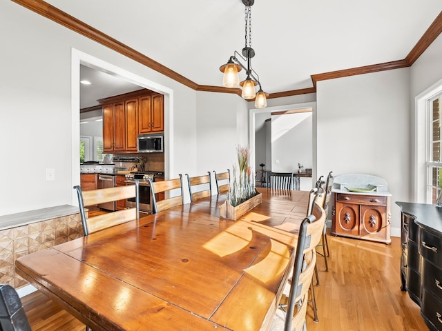 dining area with crown molding and light wood-style flooring