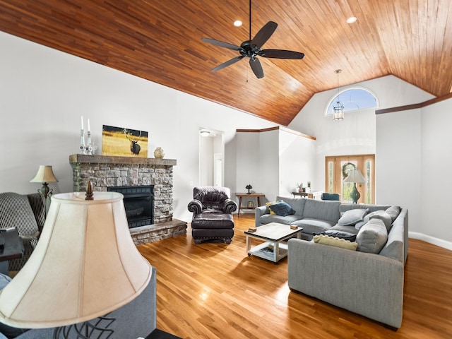 living room featuring wood ceiling, ceiling fan, a stone fireplace, wood finished floors, and high vaulted ceiling