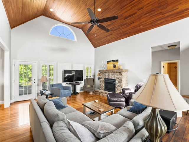 living room featuring a healthy amount of sunlight, wooden ceiling, a fireplace, and high vaulted ceiling
