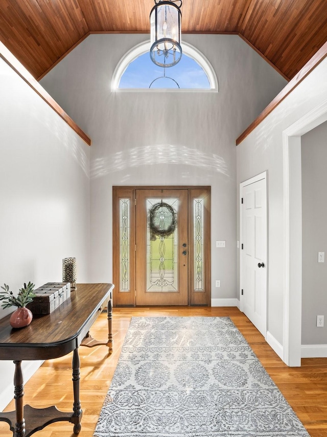 entryway featuring light wood-style floors, baseboards, high vaulted ceiling, wooden ceiling, and a notable chandelier