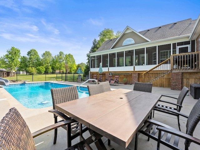 view of swimming pool with fence, a water slide, a sunroom, a fenced in pool, and a patio