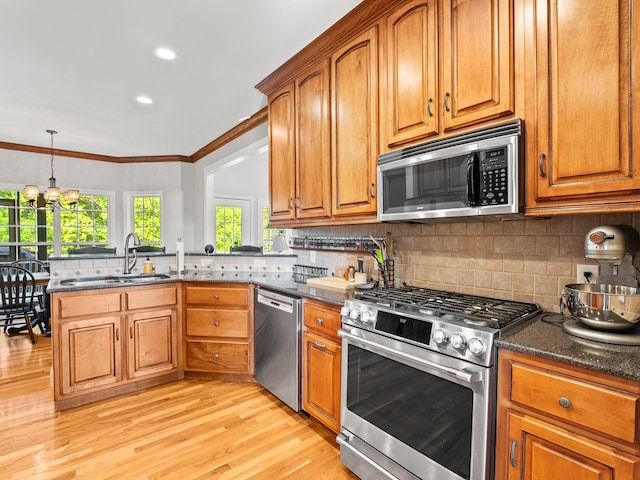 kitchen featuring a sink, light wood-style floors, brown cabinetry, stainless steel appliances, and a peninsula