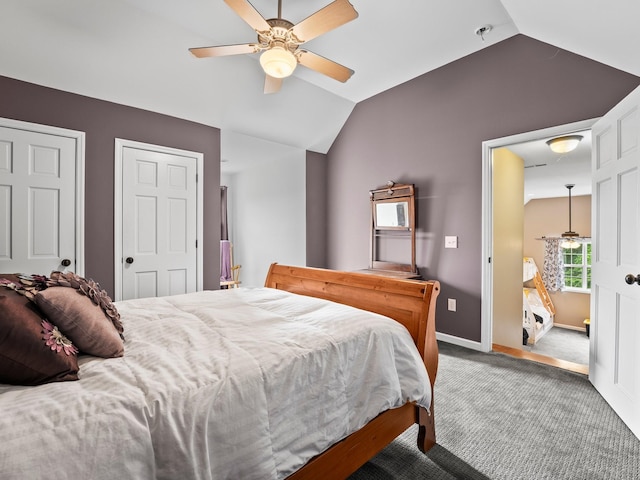 bedroom featuring carpet floors, multiple closets, lofted ceiling, baseboards, and ceiling fan