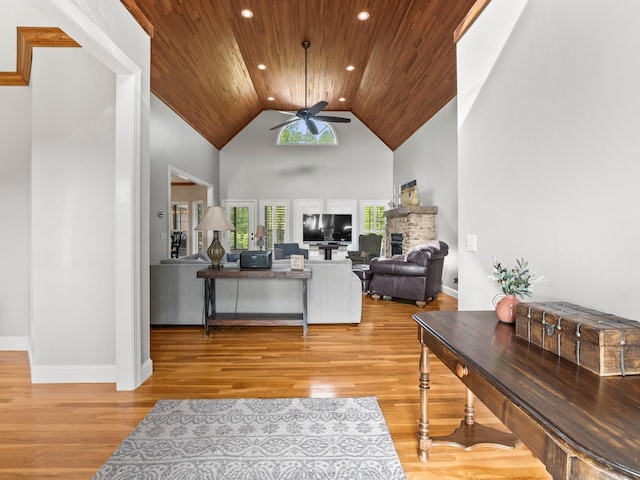 living room featuring a fireplace, light wood-style floors, ceiling fan, high vaulted ceiling, and wood ceiling