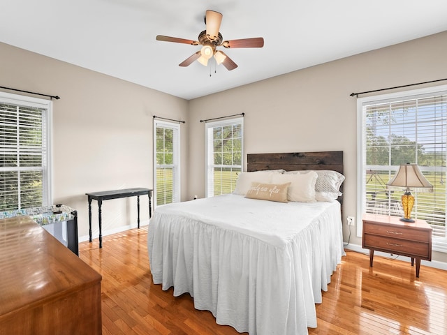 bedroom featuring wood-type flooring, a ceiling fan, and baseboards