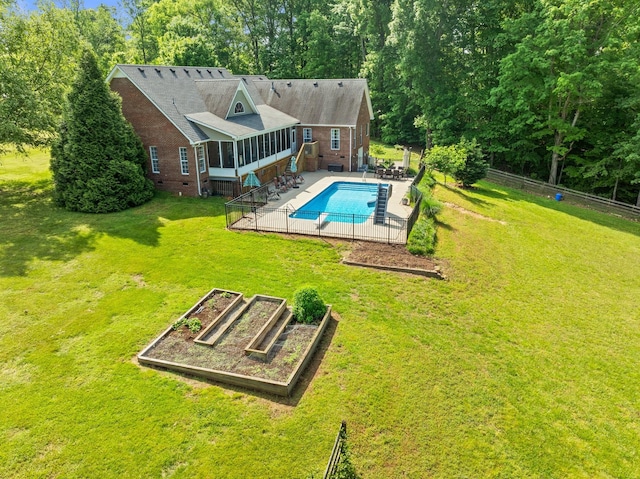 view of swimming pool with a lawn, a fenced in pool, a garden, and a sunroom