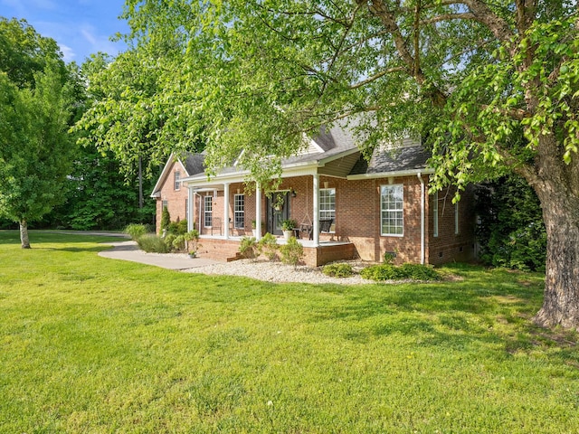 view of front of home with covered porch, brick siding, a shingled roof, and a front lawn