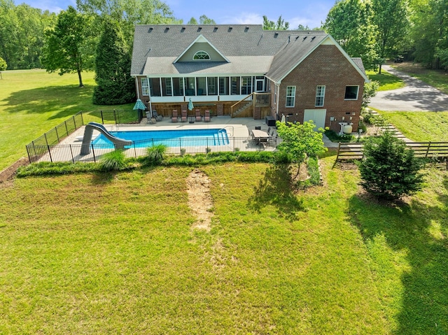 view of pool with a lawn, a water slide, stairway, and fence