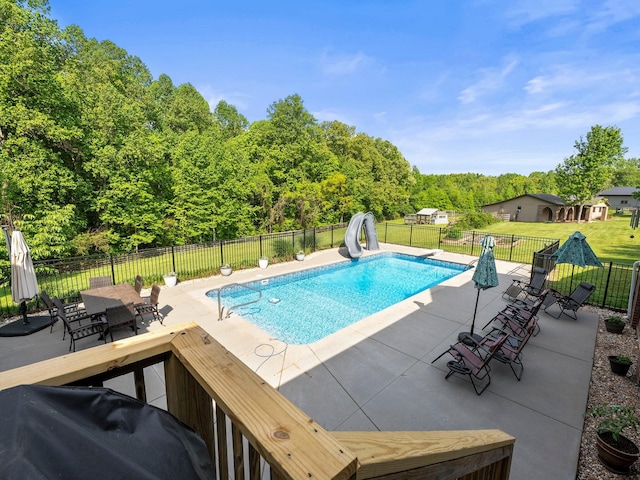 view of pool with a fenced in pool, fence, a water slide, and a patio area