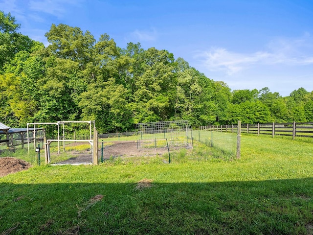 view of yard with a garden, fence, and a wooded view