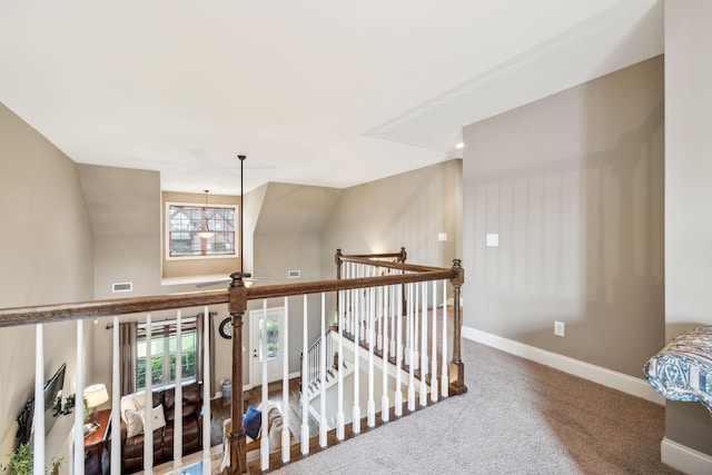 hall with visible vents, an upstairs landing, carpet floors, baseboards, and lofted ceiling