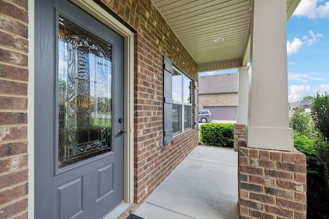 property entrance featuring brick siding and covered porch