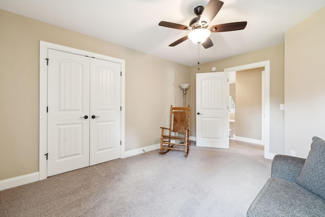 living area featuring baseboards, a ceiling fan, and carpet flooring