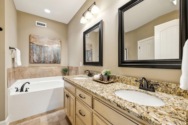 bathroom with visible vents, a sink, a garden tub, and double vanity