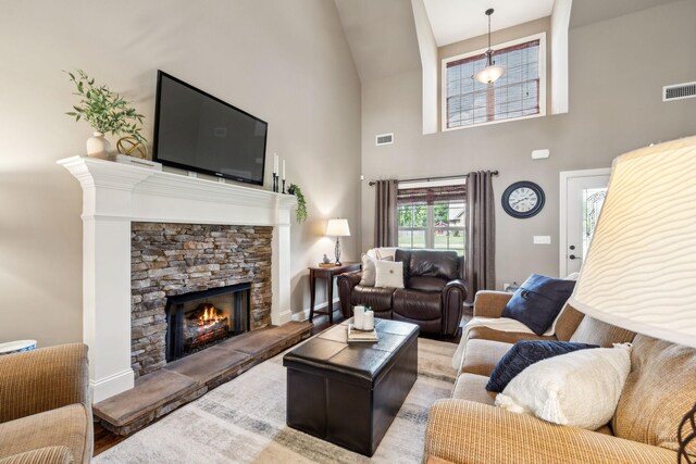 living room featuring visible vents, wood finished floors, a fireplace, baseboards, and high vaulted ceiling